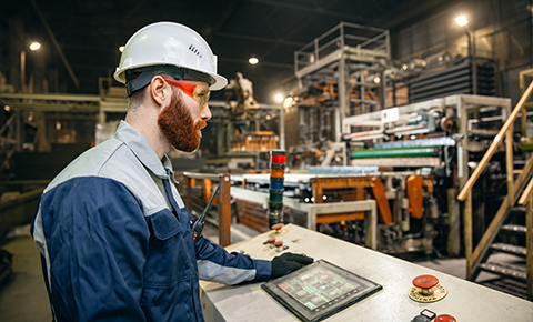 Factory operator using touchscreen control panel in automated production line