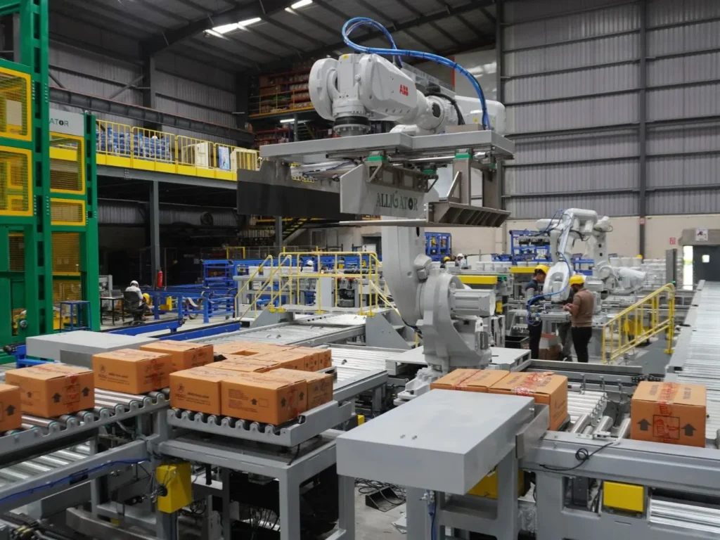 Food packaging automation system with robotic carton handling, roller conveyors, and packed boxes in a food production facility.